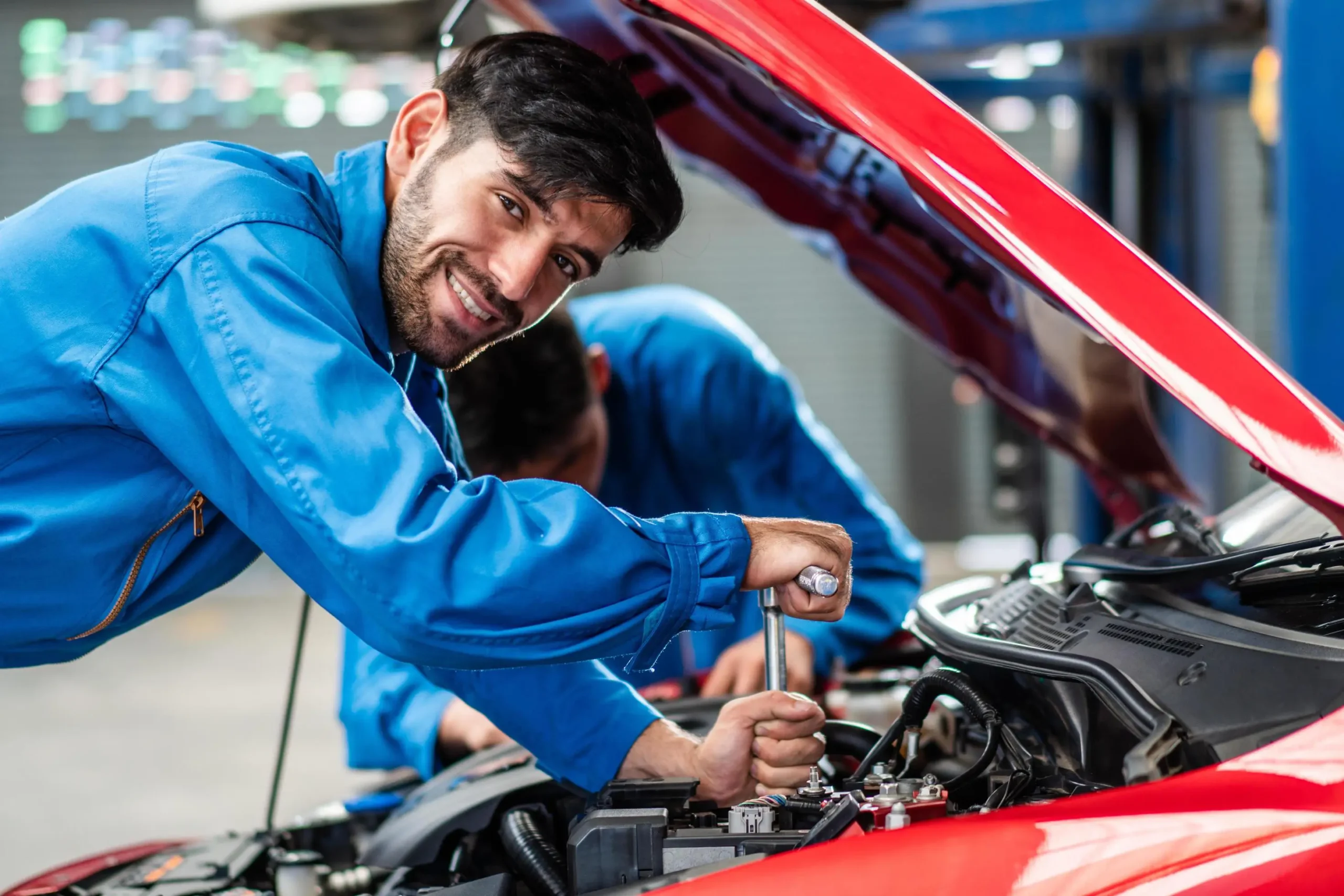 Technician working in a red car engine bay